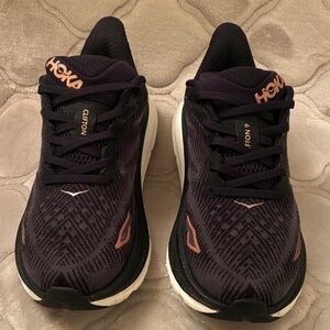 HOKA CLIFTON 9 BLACK AND BRONZE LOGO AND LETTERS